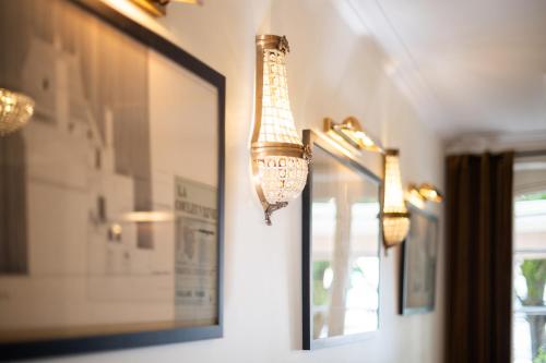 two chandeliers hanging from a wall next to a mirror at Hôtel La Couleuvrine Sarlat Centre Ville in Sarlat-la-Canéda