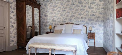 a bedroom with a white bed with blue and white wallpaper at Château de Longevergne in Anglards-de-Salers