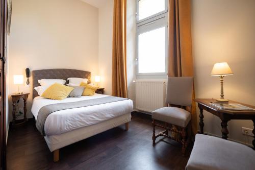 a bedroom with a bed and a desk and a window at Hôtel La Couleuvrine Sarlat Centre Ville in Sarlat-la-Canéda