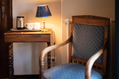 a table with a chair and a lamp on a table at Hôtel La Couleuvrine Sarlat Centre Ville in Sarlat-la-Canéda