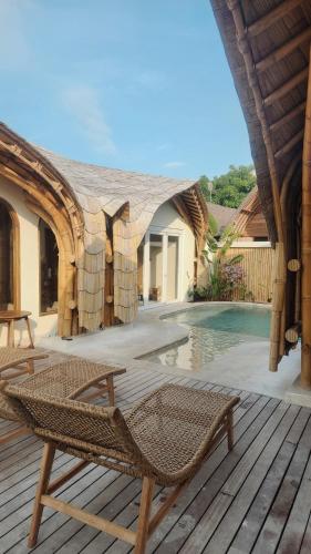 a wicker chair sitting on a deck next to a pool at Tipsea Turtle Gili Air in Gili Air