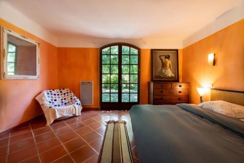 - une chambre avec des murs orange, un lit et une fenêtre dans l'établissement La Maison du Jardin de Gassin Piscine, Calme et nature, à Gassin