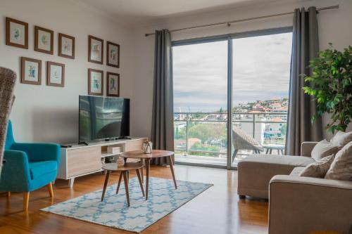 a living room with a tv and a large window at Casa da Baía Overlooking Funchal Bay in Funchal