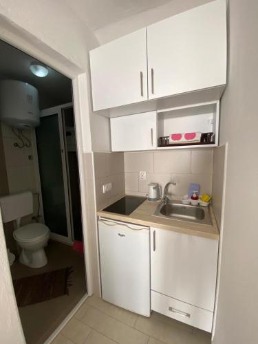a small kitchen with white cabinets and a sink at Nana Dea 2 in Utjeha