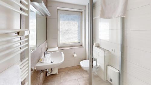 a white bathroom with a sink and a toilet at Gorch Fock - 11 in Cuxhaven