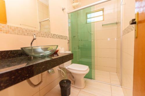 a bathroom with a glass sink and a toilet at Refúgio 4 Suítes c/ Piscina, Sinuca e Área Gourmet in Caldas Novas