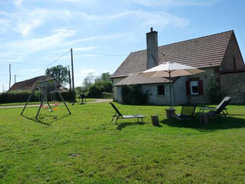 a yard with two chairs and an umbrella and a swing at Grande maison moderne avec jardin, près de châteaux et du Parc Le Pal - FR-1-489-99 in Vaumas
