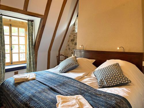 a bed with blue and white pillows in a room at Élégant cottage médiéval restauré avec piscine, cheminée, proche du golf et attractions culturelles - FR-1-489-335 in Hérisson