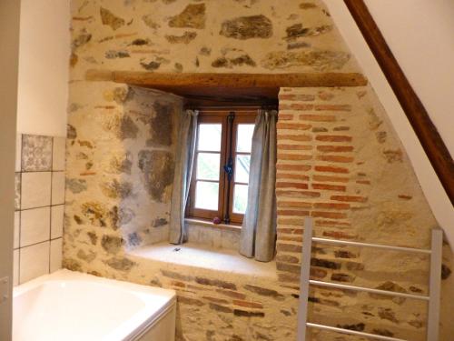 a bathroom with a stone wall and a window at Élégant cottage médiéval restauré avec piscine, cheminée, proche du golf et attractions culturelles - FR-1-489-335 in Hérisson