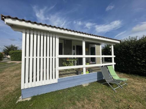 a white shed with a chair in a yard at Chalet au bord de l'eau avec terrasse, pêche, baignade surveillée, buvette et activités extérieures - FR-1-489-360 in Pierrefitte-sur-Loire