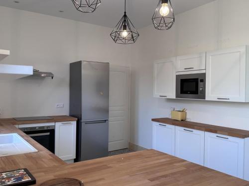une cuisine avec des armoires blanches et un réfrigérateur en acier inoxydable dans l'établissement Charmante Cure Ancienne avec Jardin et WiFi, Près de Vichy - FR-1-489-459, à Jaligny-sur-Besbre