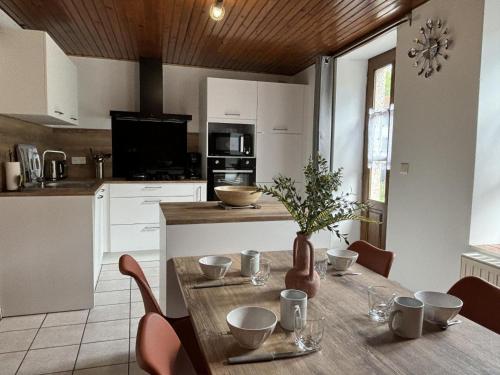 une cuisine avec une table en bois et des chaises ainsi qu'une salle à manger dans l'établissement Maison de montagne avec SPA, cheminée et activités proche voisins - FR-1-489-534, à La Chabanne