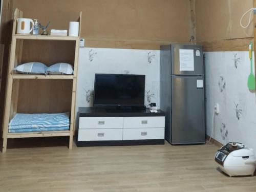 a living room with a tv and a refrigerator and a tv stand at Haneul Cheon Ddaji Hanok in Yangyang