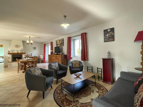 un salon avec un canapé, des chaises et une table dans l'établissement Maison de campagne avec jardin clos, cheminée et animaux, au cœur du Parc Régional du Perche - FR-1-497-91, à La Chapelle-Souëf