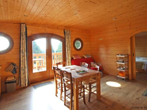 comedor con mesa y sillas en una cabaña en Chalet bois avec terrasse, animaux acceptés, nature près Alençon - FR-1-497-184, en Le Plessis