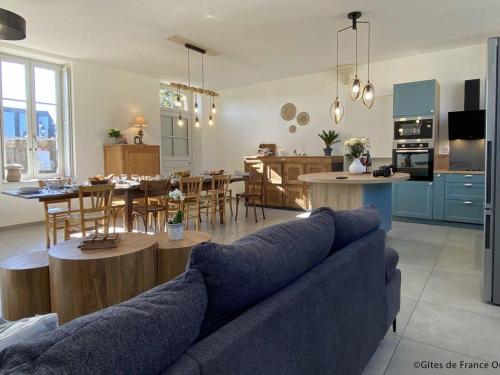 un salon et une cuisine avec un canapé et une table dans l'établissement Gîte spacieux dans le Perche avec WIFI inclus, idéal pour réunions familiales - FR-1-497-240, à Val-au-Perche