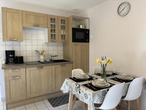 une cuisine avec une table et des chaises et une cuisine avec une horloge dans l'établissement Gîte confort au cœur de l'Allier : randonnées, canoë, pêche, vignoble, terrasse, tout inclus - FR-1-489-512, à Contigny