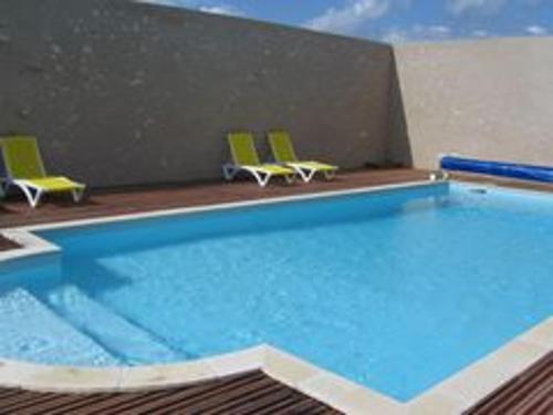 une grande piscine avec deux chaises dans l'établissement Maison avec piscine chauffée, proche Châteaux de la Loire, confort et charme, animaux acceptés - FR-1-491-355, à Averdon