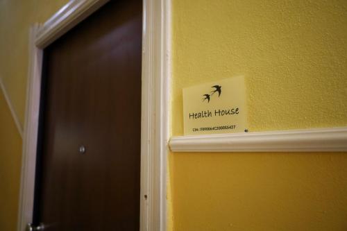 a sign on a yellow wall next to a door at Health House in Sassari