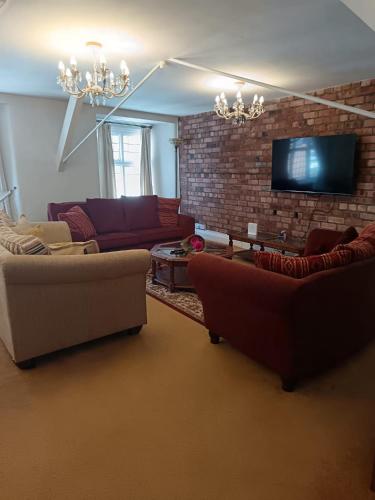 a living room with couches and a brick wall at Chandeliers 6 in Shrewsbury