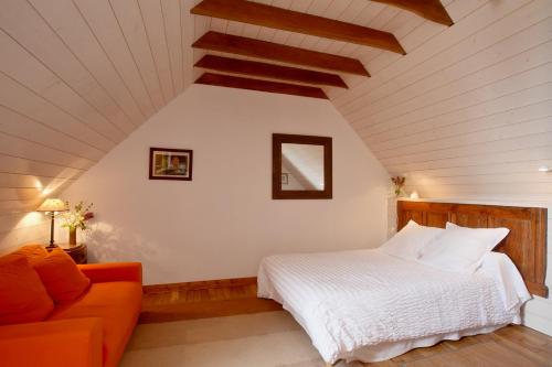 Un dormitorio con una cama y un sofá en un ático. en Chambres de la Ville d'Ys, en Cléden-Cap-Sizun