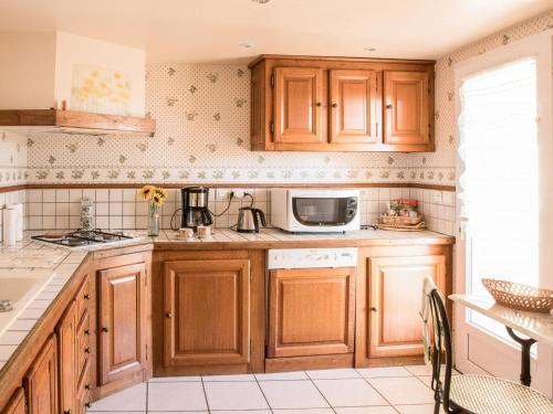 - une cuisine avec des placards en bois et un four micro-ondes dans l'établissement Maison spacieuse 3 ch, Wifi, animaux admis, terrasse, garage - Le Lardin-Saint-Lazare - FR-1-616-220, à Saint-Lazare