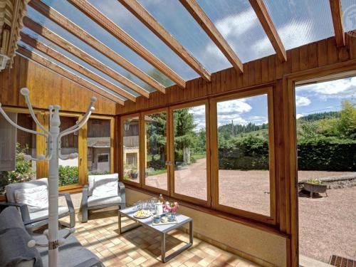 a screened in porch with a glass ceiling with windows at Gîtes confortables avec piscine, accueil animaux, cheminée, jardin - FR-1-496-140 in Belmont-de-la-Loire