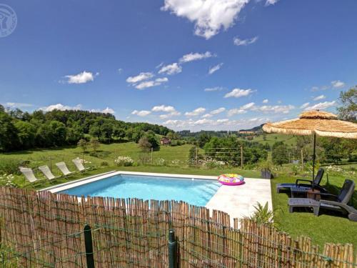 a swimming pool with an umbrella and a table and chairs at Gîtes confortables avec piscine, accueil animaux, cheminée, jardin - FR-1-496-140 in Belmont-de-la-Loire