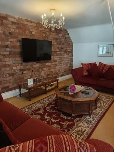 a living room with a couch and a tv on a brick wall at Chandeliers 6 in Shrewsbury