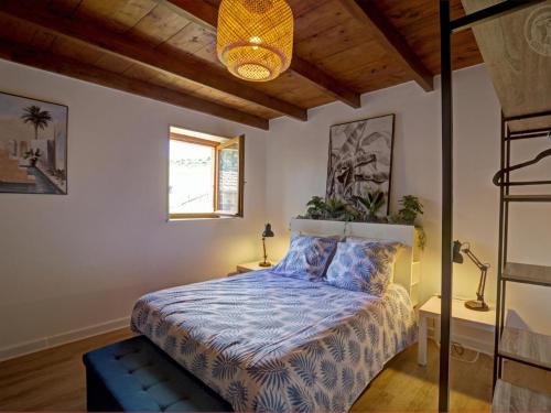 a bedroom with a bed with a blue comforter at Gîtes Champêtres Rénovés avec Terrasse, Jardin, et Activités pour Familles et Amis - FR-1-496-304 in Belmont-de-la-Loire