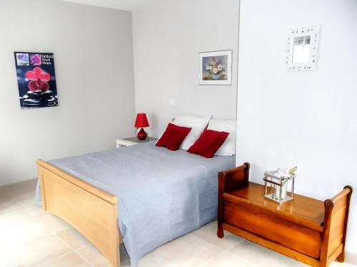 Un dormitorio con una cama con almohadas rojas y una mesa. en Maison de vacances avec piscine chauffée, spa, aire de jeux et jardin privatif en Touraine - FR-1-381-286, en Saint-Paterne-Racan