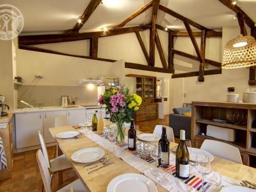 - une table à manger avec des bouteilles de vin et des fleurs dans la cuisine dans l'établissement Gîte historique entre Lyon et Saint-Étienne avec Wi-Fi, jardin, équipements bébé et proche tennis - FR-1-496-275, à Sainte-Croix-en-Jarez