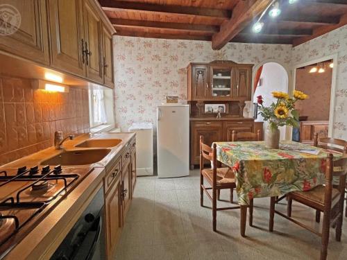 une cuisine avec une table et un réfrigérateur blanc dans l'établissement Charmant gîte à la ferme avec terrasse près de Saint-Étienne, 1 chambre, wifi, animaux acceptés - FR-1-496-144, à Saint-Héand