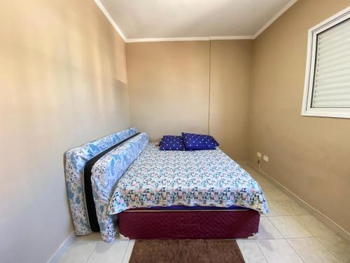 ein kleines Schlafzimmer mit einem Bett mit blauen Kissen in der Unterkunft Apto c/ vista mar e piscina no prédio perto do mar in Samaritá