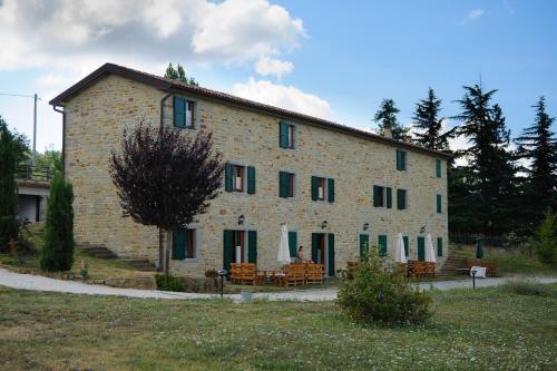 un grande edificio in mattoni con sedie di fronte di Agriturismo Prato Grande a Loiano