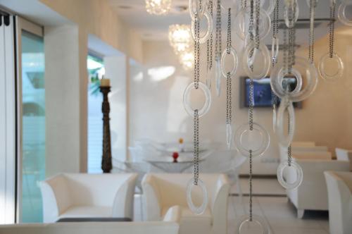 ein Esszimmer mit weißen Stühlen und einem Kronleuchter in der Unterkunft Hotel Caribia Pinarella in Cervia
