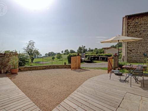 a patio with a table and an umbrella and chairs at Gîte spacieux avec terrasse en forêt, 12 lits, proche randonnées - FR-1-496-314 in Verrières-en-Forez