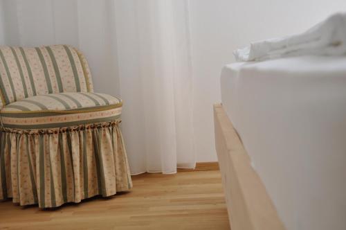 a chair sitting in a room next to a bed at Alpenchalet Apartments in Parcines
