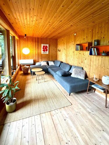 a living room with a blue couch and a table at Architectural Cottage On 7000 Sqm Nature Plot in Hadsund
