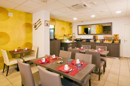een restaurant met tafels en stoelen en een keuken bij Residhome Reims Centre in Reims