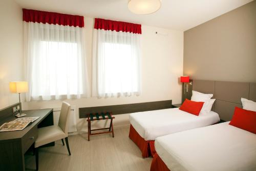 a hotel room with two beds and a desk at Residhome Reims Centre in Reims