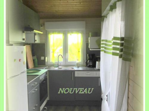 une petite cuisine avec un évier et un réfrigérateur dans l'établissement Charmants chalets au bord du lac avec terrasse, activités nautiques et pêche, animaux acceptés, tout inclus - FR-1-489-361, à Pierrefitte-sur-Loire