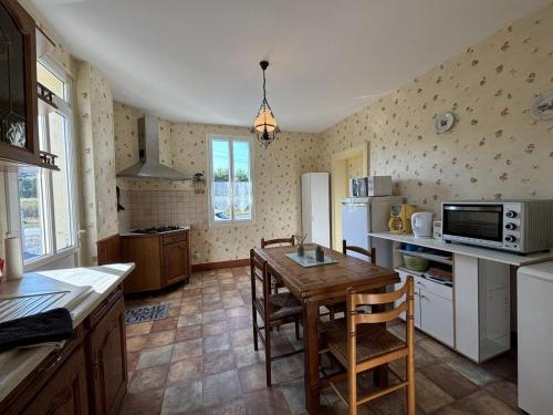 une cuisine avec une table en bois et un micro-ondes dans l'établissement Maison avec jardin près du canal et de la Loire, équipement complet, parfait pour familles - FR-1-489-550, à Diou