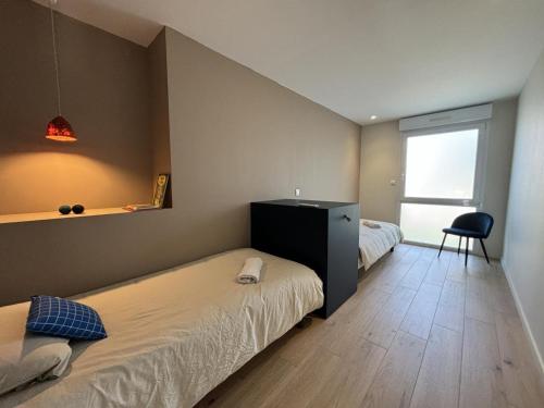 ein Schlafzimmer mit zwei Betten und einem Schreibtisch und einem Stuhl in der Unterkunft Gîte contemporain avec climatisation et parking dans un village historique - FR-1-489-551 in Ébreuil