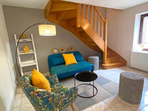 a living room with a blue couch and a staircase at Gîte cosy avec spa, grand jardin, proche de la rivière Sioule - idéal pour famille et relaxation - FR-1-489-342 in Saint-Bonnet-de-Rochefort