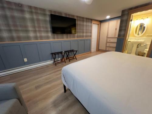 a bedroom with a bed and a tv and a couch at Stonehurst Manor Breakfast & Dinner Included in North Conway
