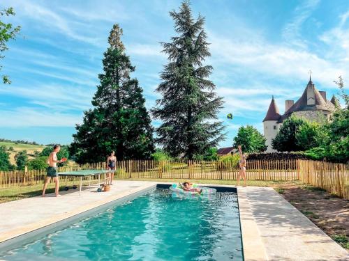 un groupe de personnes dans une piscine avec un château en arrière-plan dans l'établissement Gîte authentique avec piscine partagée, jardin et wifi à Saint-Étienne-de-Vicq - FR-1-489-275, à Saint-Étienne-de-Vicq