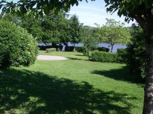 a park with green grass and trees and a lake at Chalets indépendants en camping 2 étoiles avec terrasse – Idéal famille, activités et jeux pour enfants - FR-1-489-405 in Treignat