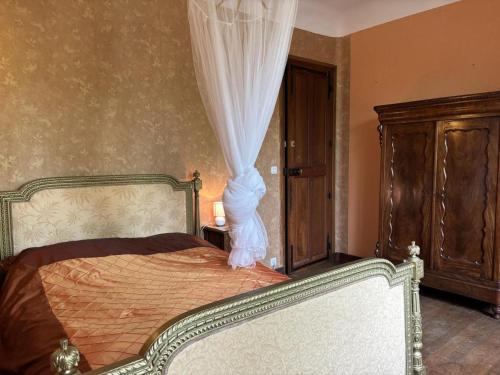 a bedroom with a bed with a curtain and a dresser at Villa de charme avec jardin clos, proche de Vichy, idéale pour séjours en famille - FR-1-489-533 in Sanssat