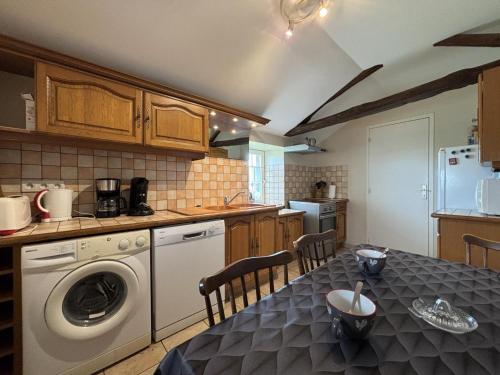 a kitchen with a table with a washing machine at Fermette rénovée avec jardin clos, animaux acceptés, WiFi et parking - FR-1-489-87 in Bourbon-lʼArchambault